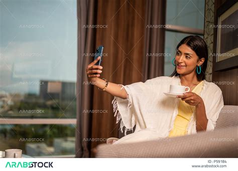 امرأة عربية خليجية سعودية ترتدي زي صيفي، الاستمتاع بالعطلة داخل المنزل، التقاط صورة تذكارية من