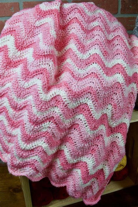 A Pink And White Crocheted Blanket Sitting On Top Of A Wooden Chair