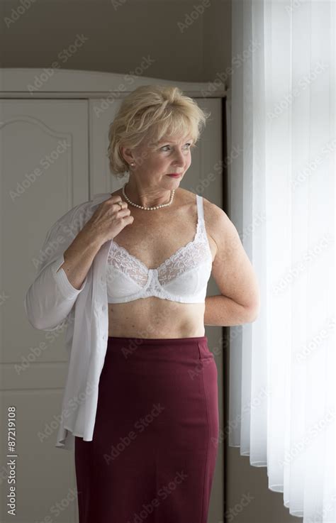 Elderly Woman Getting Dressed Putting On A White Shirt Stock Photo