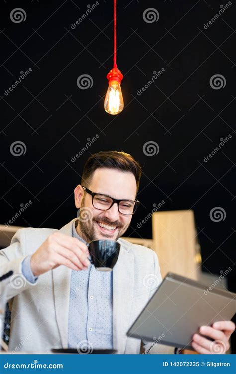 Young Businessman Using A Tablet And Drinking Coffee While Working In A