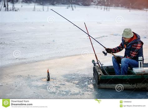 Ice Fishing On Frozen Lake Fisherman Fishing On Ice Stock Photo