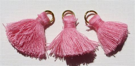 Three Pink Tasselled Keychains With Gold Rings On White Background