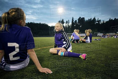 Girls Relaxing On Soccer Field Against Sky Stock Photo Dissolve