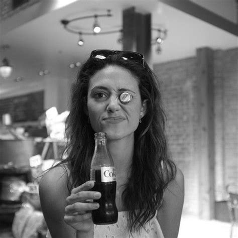 a woman holding a beer in her right hand and looking at the camera with an evil look on her face