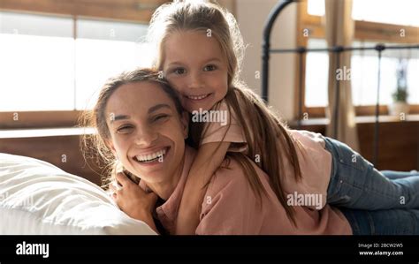 Happy Woman Lying On Bed With Daughter On Back Stock Photo Alamy