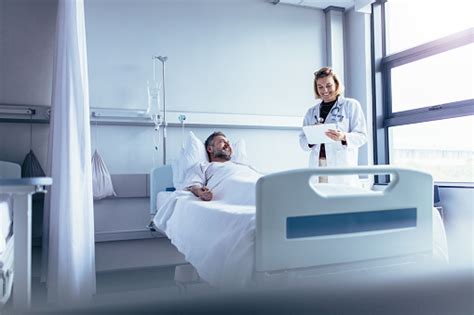 Doctor Attending Sick Patient In Hospital Bed Fotografie Stock E