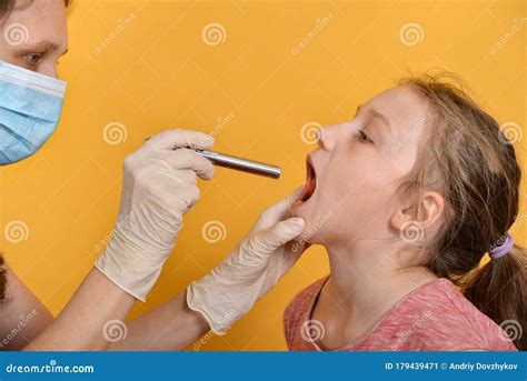 A Female Doctor Examines A Girl`s Oral Cavity With A Diagnostic Medical Flashlight Stock Image