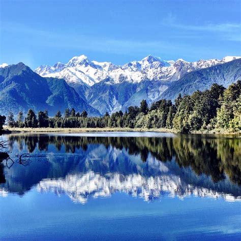 Snow Capped Mountain Reflection Into Blue Clear Lake Stock Photo