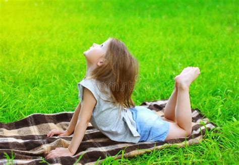 Little Girl Child Lying On The Grass Does Yoga Exercise Stock Image