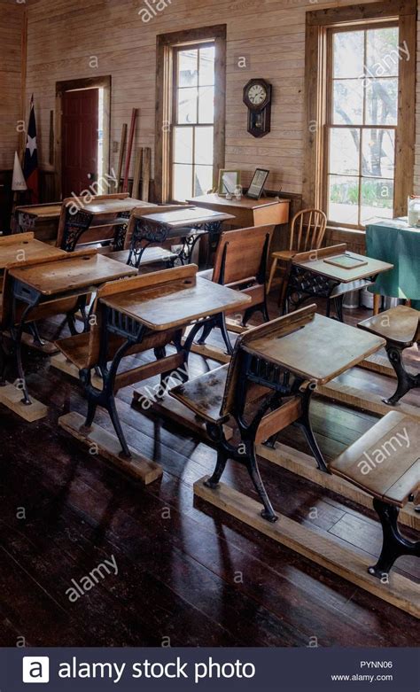 An Old School Room With Wooden Desks And Chairs In The Center Looking