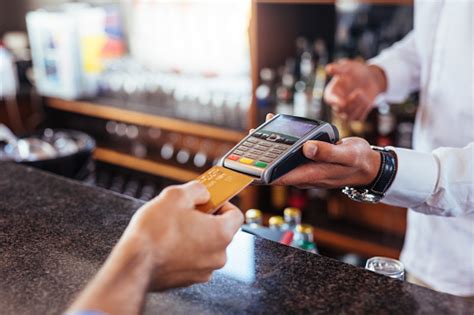 What are the kotak debit card transaction fees if i swipe my card at fuel pumps or booking railway tickets? Customer Making Payment Using Credit Card At Bar Stock Photo - Download Image Now - iStock
