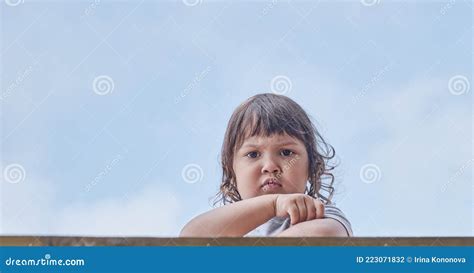 Portrait Of Cute Little Asian Frowning Baby Girl With Dark Hair On Blue