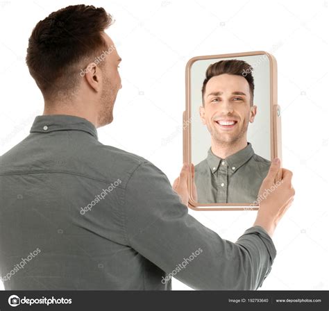 Young Man Holding Mirror And Looking At Himself On White Background