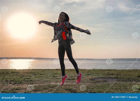 Silhouette Of Carefree Young Woman Near River At Sunset Stock Image