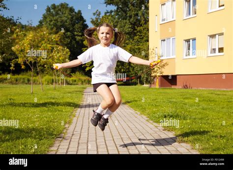 Little Girl In White Shirt And Black Shorts Jumping Rope Outside Stock