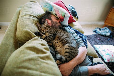 High Angle View Of Man With Cat Sleeping On Sofa At Home Stock Photo