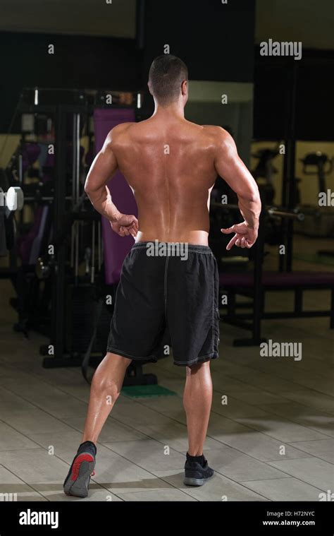 Young Man Standing Strong In The Gym And Flexing Rear Lat Spread Pose
