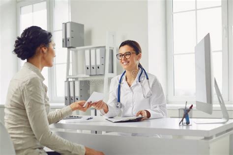 Smiling Female Patient At Consultation With Woman Doctor Sitting At