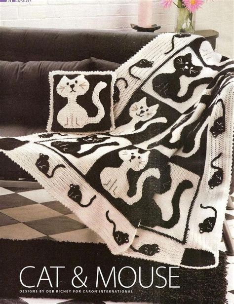A Black And White Cat Afghan Sitting On Top Of A Couch