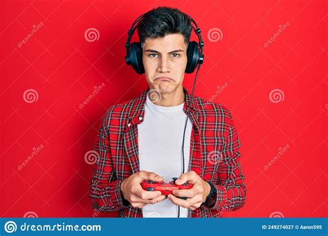 Young Hispanic Man Playing Video Game Holding Controller Depressed And