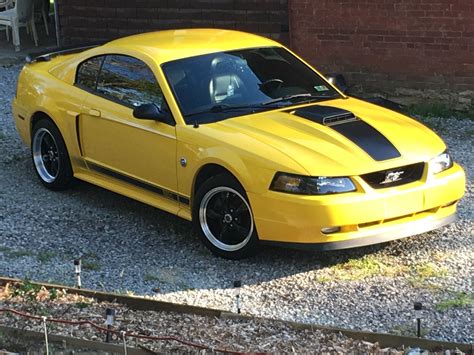 A Yellow Mustang Parked In Front Of A Brick Building
