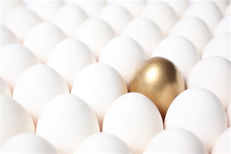 Golden Egg Standing Out From A Crowd Of Ordinary Eggs Stock Photo