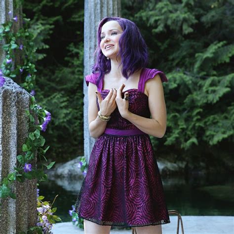 A Woman With Purple Hair Is Standing In Front Of Some Trees And Flowers
