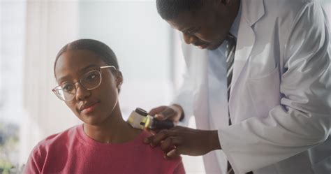 African American Dermatologist Using A Dermatoscope To Identify
