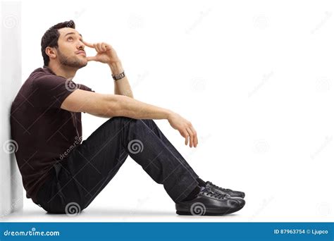 Pensive Young Man Sitting On The Floor And Looking Up Stock Photo