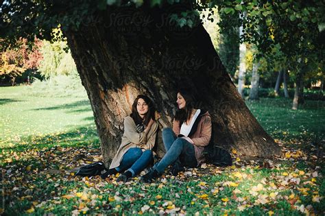 Two Beautiful Female Friends Sitting Below The Tree In The Park By Stocksy Contributor Mak