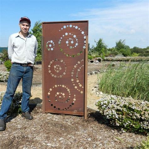 A Man Standing Next To A Large Metal Sign