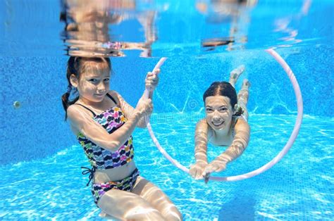 Children Swim In Pool Underwater Girls Have Fun In Water Stock Photo