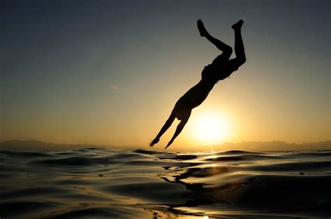Premium Photo Man Jumping Into The Sea At Sunset