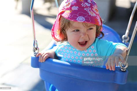 Portrait Of Baby Girl Sitting On Blue Baby Swing High Res Stock Photo