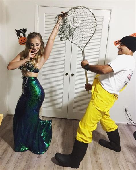 A Man And Woman Dressed Up In Costumes One Is Holding A Net While The