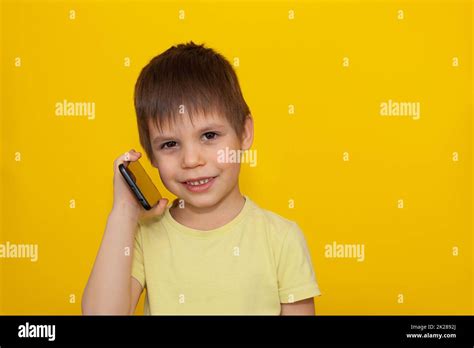 Little Kid Playing Games On Smartphone Over Yellow Background The