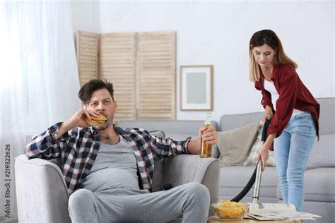 Lazy Husband Watching Tv And His Wife Cleaning At Home Stock Foto
