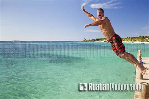 Man Jumping Off Pier Into Caribbean Sea Roatan Photography