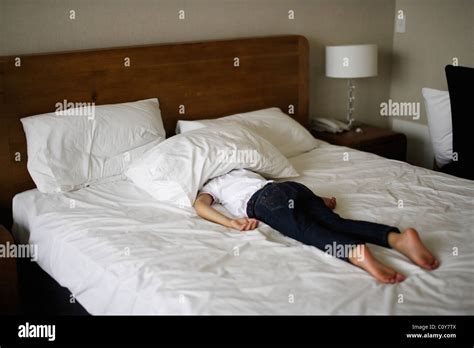 Girl Lies On Stomach On Bed With Head Under Pillow Stock Photo Alamy