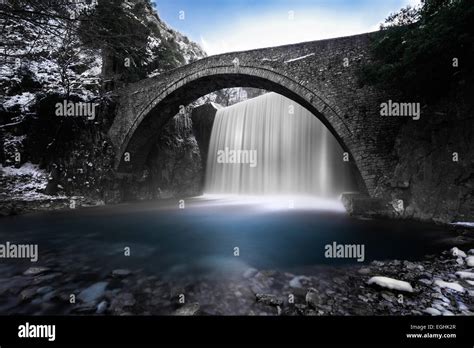 Waterfall Flowing Under An Arched Stone Bridge Stock Photo Alamy