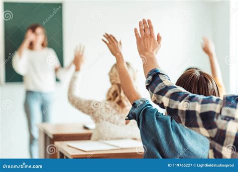 Students Raising Hands With Teacher In Lecture Hall Royalty Free Stock