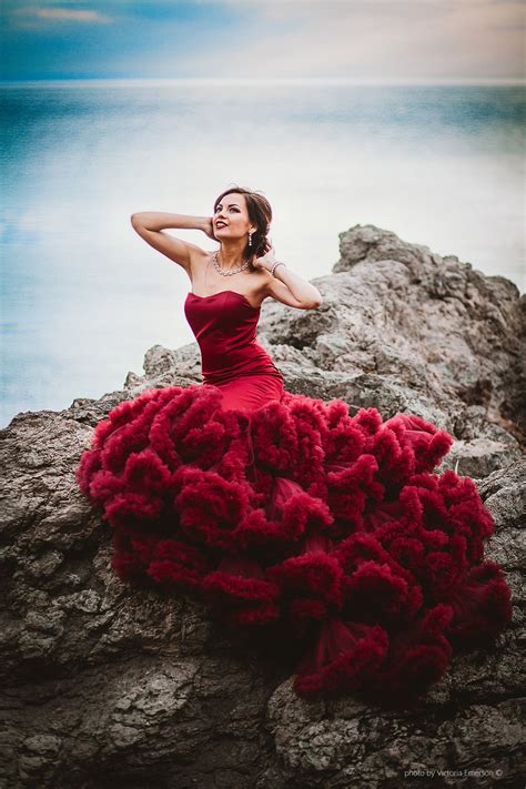 Фото Девушка в красном платье сидит на камне на фоне моря фотограф Виктория Эмерсон