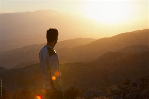 Young Man Looking Out Over A Sunset From Mountain Viewpoint By