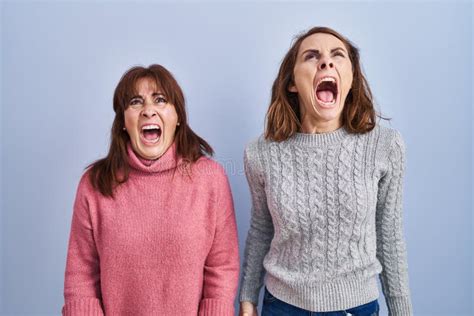 Mother And Daughter Standing Over Blue Background Angry And Mad
