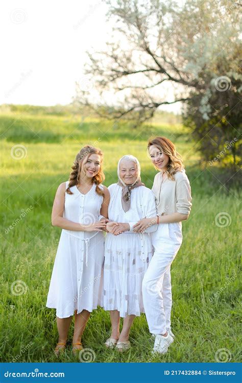 Old Granny Standing With Adult Granddaughters In White Dresses Stock