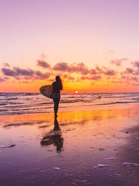 Surf Woman With Surfboard On A Beach At Sunset Or Sunrise Stock Photo