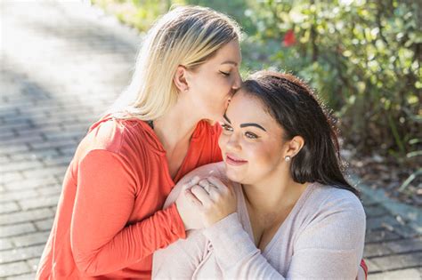 Young Lesbian Couple In The Park Kiss On Forehead Fotografias De