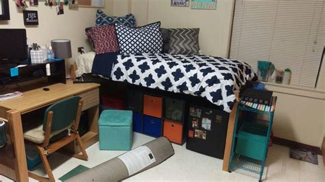 A Dorm Room With A Bed Desk And Computer On Top Of The Dressers