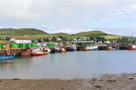Several Boats Are Docked In The Water Near Some Hills And Green Hills