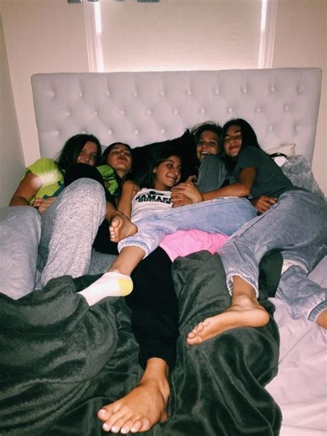 A Group Of People Laying On Top Of A Bed In A Room With White Walls